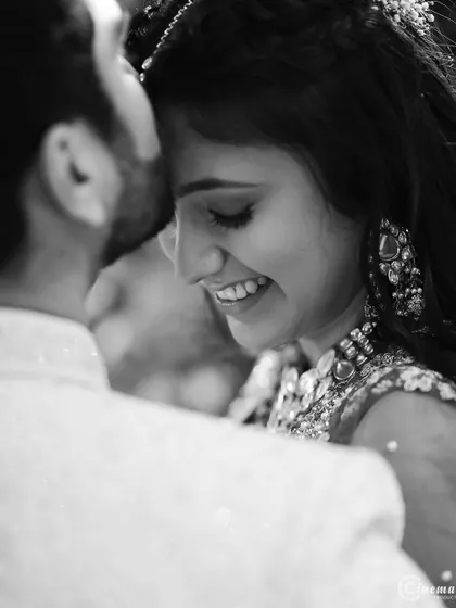 The groom's gentle kiss on the bride's forehead, captured in a timeless black and white close-up that radiates warmth and affection.