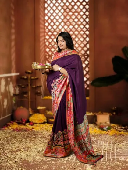 This mother-to-be looks so elegant in a purple saree, holding a puja thali. The studio is decorated with flowers, creating a festive and traditional atmosphere for her maternity photos.