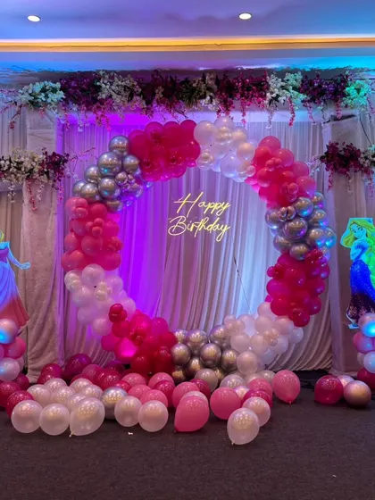 A princess-themed party featuring a large balloon ring in pink, white, and silver, with illuminated cutouts of Disney princesses like Aurora and Cinderella.