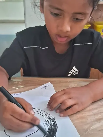 A kindergartener carefully colors in his drawing, learning about the different layers that make up our planet in a creative and memorable way.