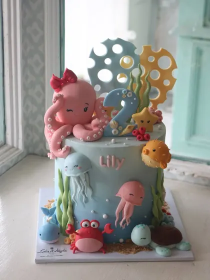 An under-the-sea cake for a second birthday, featuring a whole host of cute sea creatures like an octopus, jellyfish, and crab, all made from fondant.
