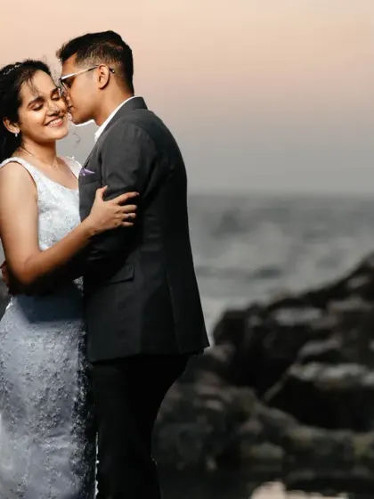 A tender kiss on the cheek against a soft sunset sky. This post-wedding portrait on the rocks is all about capturing a quiet, romantic moment in a beautiful, natural setting.