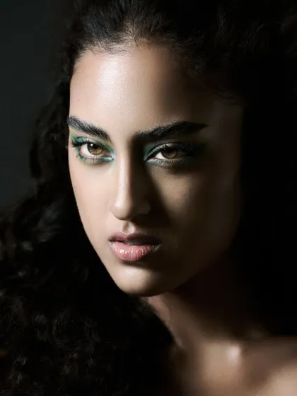 A close-up beauty shot with a focus on the eyes. The green eyeshadow is the central element, and the lighting is carefully placed to make the color vibrant and the skin luminous.