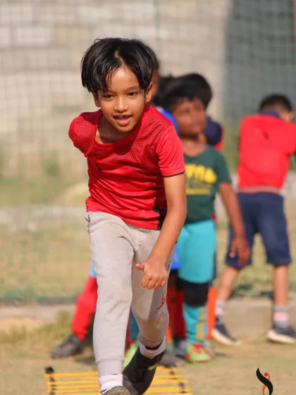 A duplicate of image 51, showing a young player's focused effort during a summer camp agility drill.