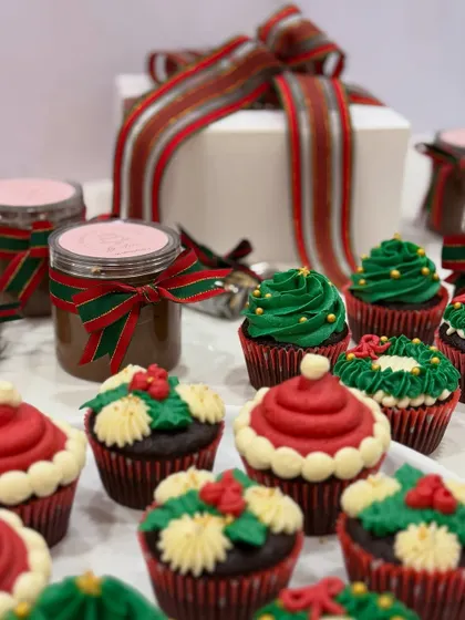 My Christmas collection, featuring festive cupcakes and jars of my house-made caramel sauce, all ready for gifting with beautiful holiday ribbons.