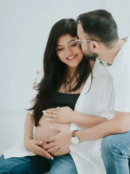 A sweet kiss on the cheek in a minimal studio setting. This classic couple maternity pose is timeless and full of affection.