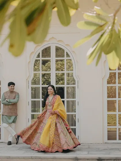 A joyful twirl in front of the elegant architecture of The Oberoi Sukhvilas. This shot captures the bride's beautiful lehenga and the happy energy of the day.