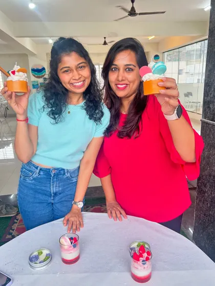Two friends proudly holding up the cupcake candles they designed and created together.