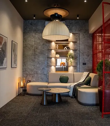 Another view of the lounge, separated by a striking red mesh screen that adds an industrial touch while maintaining an open feel. Framed art and a large pendant light complete the look.