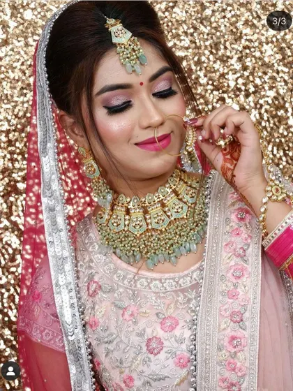 This bride looks beautiful in a pastel pink lehenga with a contrasting mint green Kundan necklace. This is a very popular color combination for modern brides.