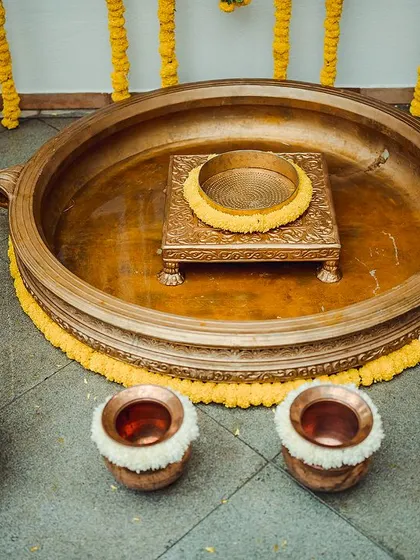 Another close-up of the brass urlis and pots, adorned with marigolds and tuberoses. These elements are essential for an authentic and traditional Haldi setup.