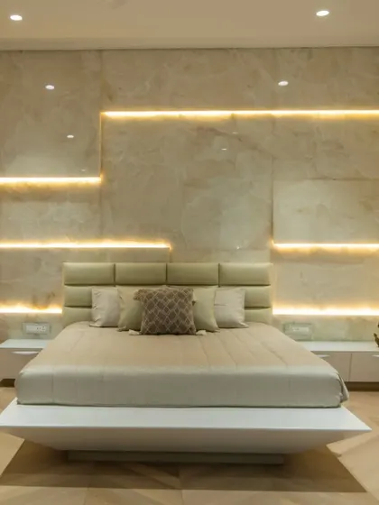 This bedroom uses layered lighting against a stone-paneled wall to create a warm and inviting ambiance. The floating bed design adds to the modern, uncluttered feel of the space.