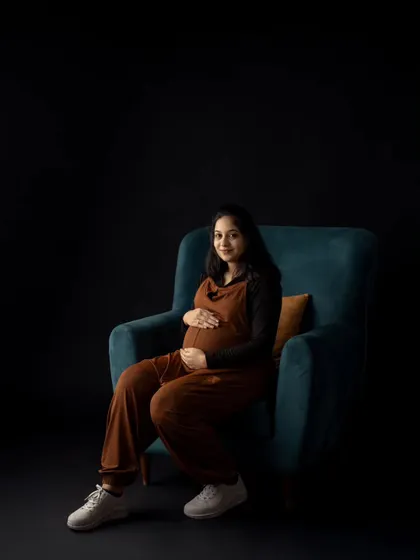 A moody and modern portrait using a single chair against a black background. The dramatic lighting creates a sophisticated and artistic feel.
