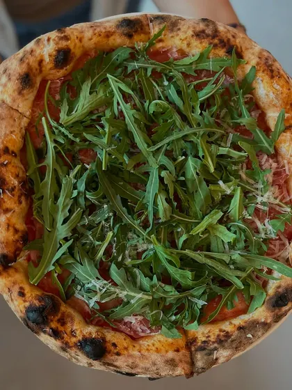 Holding our Prosciutto di Parma e Rucola pizza. It's a work of art.
