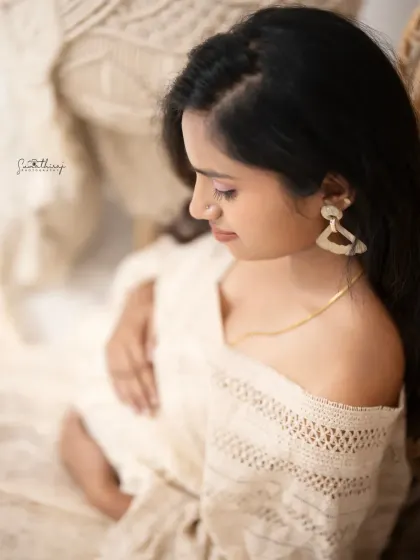 A serene and thoughtful portrait of a mother-to-be in a boho-chic setting. The soft focus and warm tones create a dreamy and intimate feel.