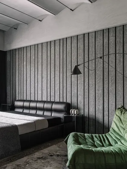 The son's bedroom, a cozy space with a predominantly monochrome palette, broken by a pop of green in the armchair and artwork.