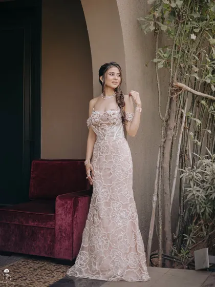 A full-length portrait of the Carnival look. The soft makeup and elegant hairstyle work in perfect harmony with the stunning off-white lace dress.
