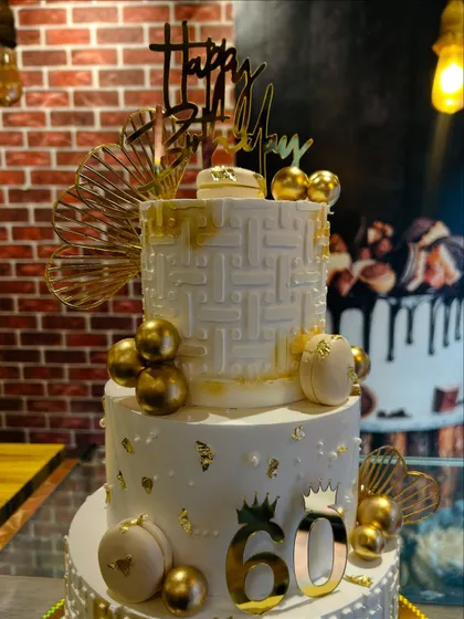 A detailed shot of the top tiers of the 60th birthday cake, highlighting the intricate texture and gold leaf accents.