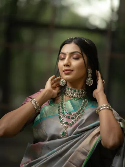 A portrait focused on the bride's serene expression and her stunning emerald jewelry. The soft, natural background keeps the attention entirely on her.