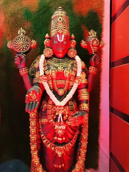 A close-up of a Venkateshwara Swamy idol under red lighting, creating a powerful and divine ambiance.