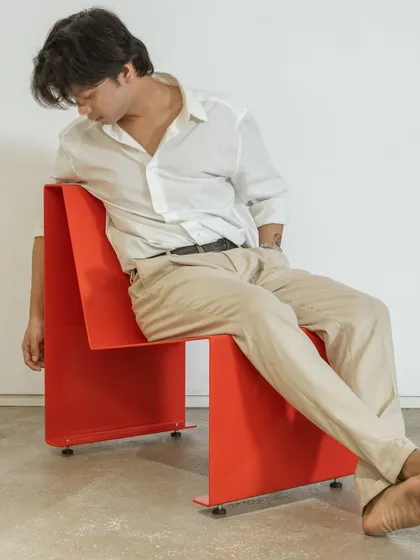 The chair's simple, durable form is designed to be a piece of functional art. Here, it provides a moment of rest, its clean lines contrasting with the human form to highlight its pure, geometric design.