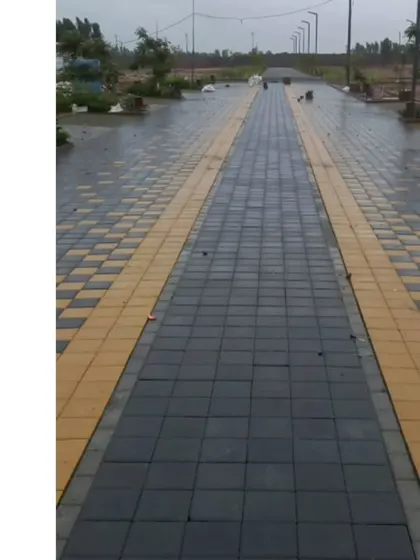 The main paved thoroughfare of a new residential layout. The design uses a combination of black and yellow pavers to create a clear and aesthetically pleasing streetscape for both pedestrians and vehicles.