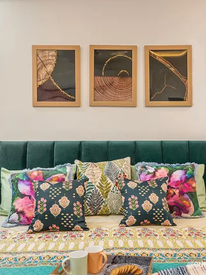 A closer look at the beautiful emerald green bed, styled with a mix of floral and patterned cushions. The bedside features an integrated, back-lit mirror that doubles as a dressing area.