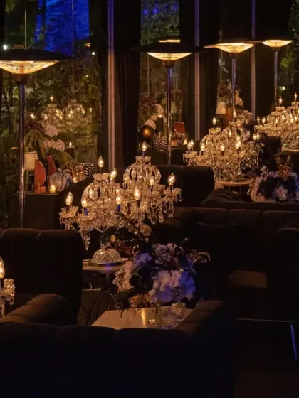 The lounge area of the black and gold themed event, where individual crystal candelabras on each table create an intimate yet opulent atmosphere. The dark, plush seating invites guests to relax in a space defined by moody elegance.