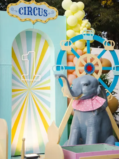 A close-up of the circus-themed decor, featuring a light-up number '1', a whimsical ferris wheel, and an adorable elephant prop. The pastel color palette gives this classic theme a soft and modern feel.