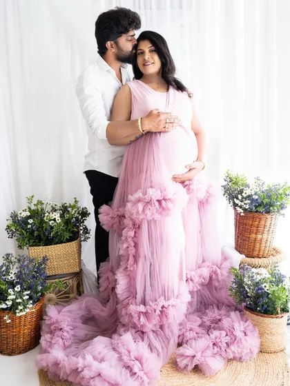 A loving embrace from behind, with the partner kissing the mom-to-be's head as they both hold the baby bump.