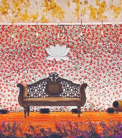 This reception backdrop combines a dense wall of red and white flowers with a central lotus motif, flanked by traditional lamps for a look that is both modern and culturally rooted.