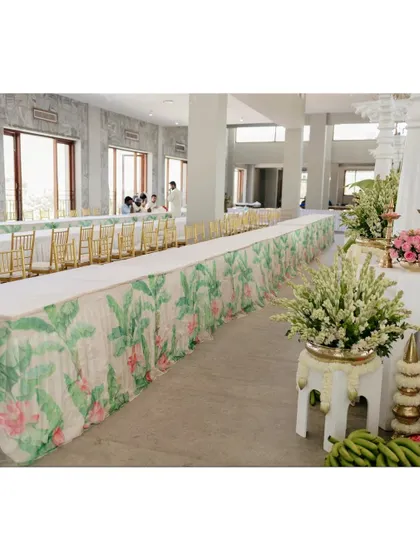 The long dining tables are covered with a custom-printed fabric featuring a banana leaf pattern.