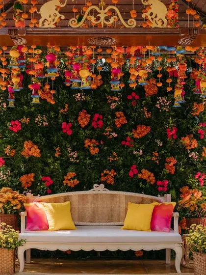The main seating for the Haldi ceremony, featuring a lush backdrop of bougainvillea and a ceiling adorned with colorful Jaipuri hangings.