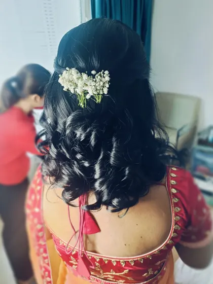 A back view of a half-up hairstyle with defined curls and a simple baby's breath accessory. This is a timeless look for an engagement or reception.
