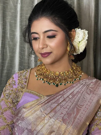 Dressed in serene pastels, this bride radiates elegance. Her lavender Kanjeevaram is paired with a soft, glamorous makeup look and a traditional bun adorned with white roses.