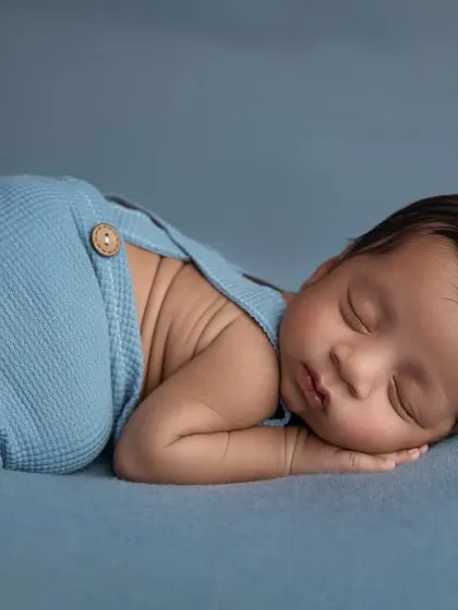 A simple and classic side pose in blue knit pants, showing off the baby's adorable back rolls.