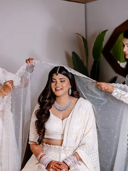 The dupatta setting is such a special tradition. Her serene smile and the delicate veil create a truly beautiful image.