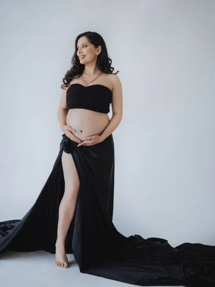 A confident and beautiful solo maternity portrait. The simple black wrap and bare bump create a modern and striking look.