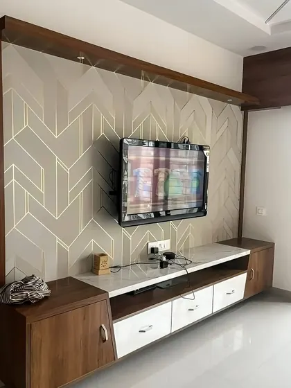 This TV unit is set against a striking geometric-patterned wallpaper. The custom console mixes wood and white finishes with angled cabinet doors, adding to the modern, graphic feel of the space.