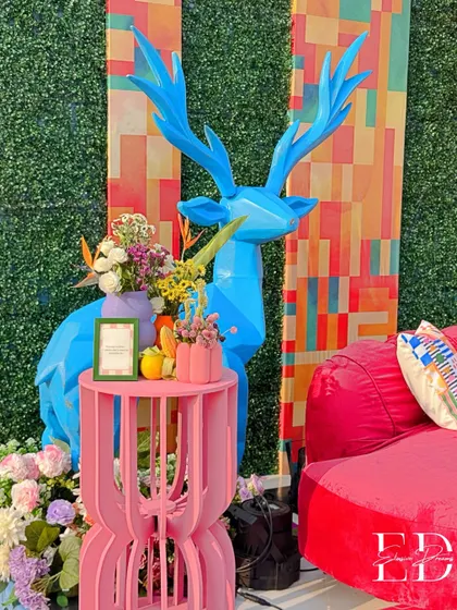 Another angle of the blue deer sculpture, this time paired with a bright red lounge sofa, showcasing the event's bold color palette.