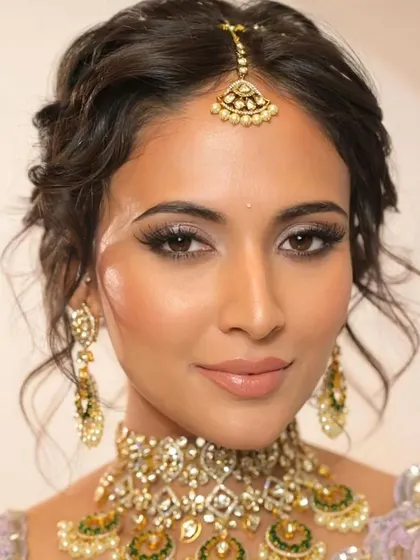 A front view of the trending tousled updo. The soft tendrils framing the face add to the romantic and modern feel of the hairstyle.