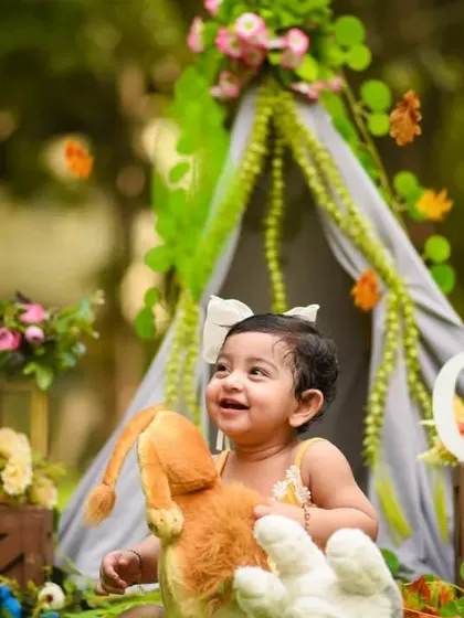 A happy moment from Shivya's outdoor jungle-themed shoot. The natural background complements the teepee and animal props perfectly.