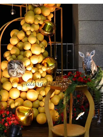 A fun and glamorous corner at a 40th birthday party. A large balloon arrangement in peach and gold is paired with a zebra statue, adding a playful and unexpected element to the decor.