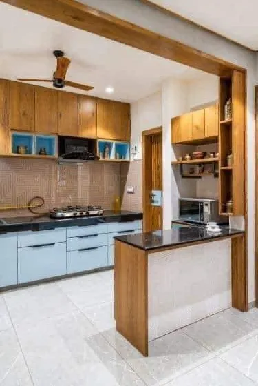 This kitchen combines light blue base cabinets with natural wood uppers for a fresh, Scandinavian-inspired look. The small breakfast counter is a smart addition for extra prep space or a casual dining spot.