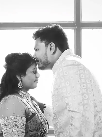 A tender moment captured in black and white. This photo shows the man kissing his partner's forehead, a classic and heartfelt pose that tells a story of love and affection.