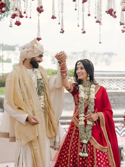 A joyful, celebratory moment between Nikita and Rishabh during their wedding ceremony in Udaipur. Her smile and their raised hands capture the excitement perfectly.
