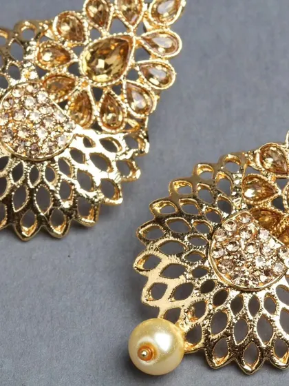 A close-up of the golden filigree earrings, highlighting the sparkling stones and delicate metalwork.