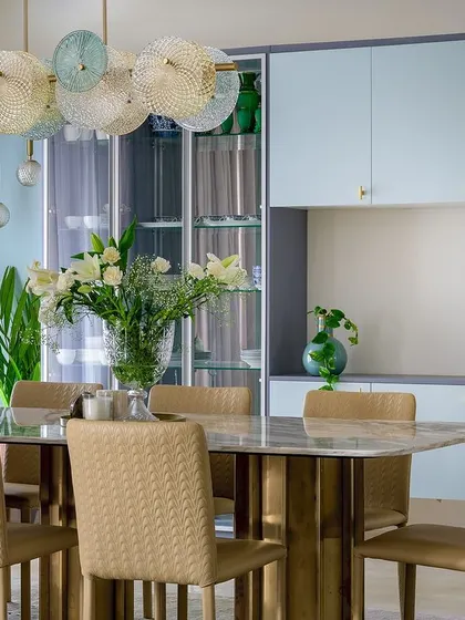 This dining room combines soft powder blue cabinetry with a striking marble-topped table and an artistic glass chandelier. It's a perfect example of how we use color and lighting to create an elegant atmosphere for gatherings.