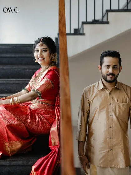 A lovely portrait of the bride sitting on a staircase, with the groom in the background.