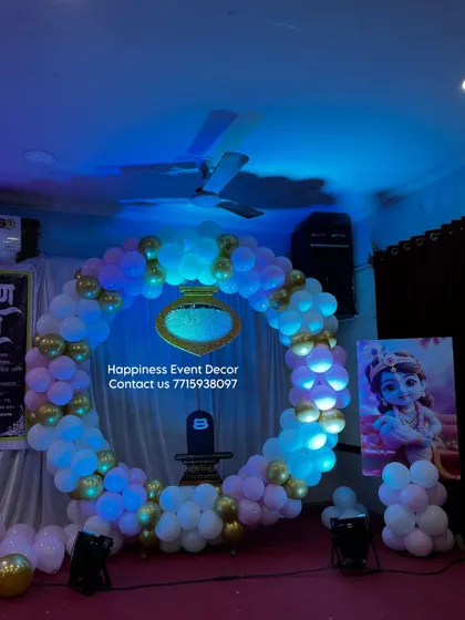 A Krishna-themed naming ceremony with a balloon ring in pink, white, and gold. The setup includes a small shivling prop and a picture of Lord Krishna, blending devotion with celebration.